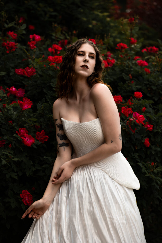 Soft light filtering through foliage on bridal portrait outdoors at Northampton House, capturing texture, mood, and movement. With a red rose bush in the background