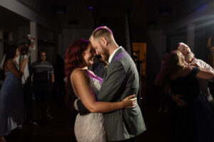 Bride and groom share an intimate first dance surrounded by guests inside The Caledonia, a historic wedding venue in Layton, Utah, captured in warm, cinematic light.