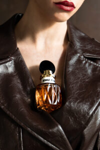 Miu Miu Miutine Eau de Parfum 100 ml nestled into the collar of leather trench coat of a model